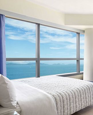 Hotel bed with window overlooking lake and mountains.