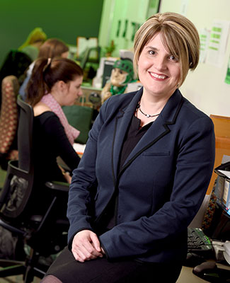 Lisa Parker poses in the MSU Alumni Association offices as work goes on behind her.