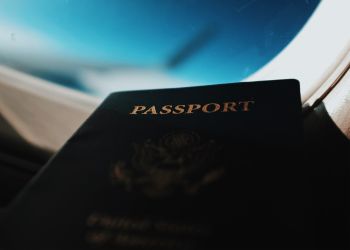 U.S. passport sits in front of airplane window.