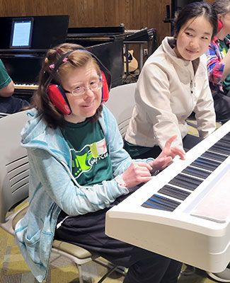 A music therapy camp attendee plays the piano.