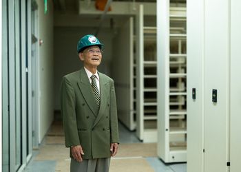 Keelung Hong standing in the new special collections space with a construction helmet