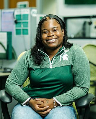 Portrait of Ariel Downs sitting inside the MSU Greenline call center.