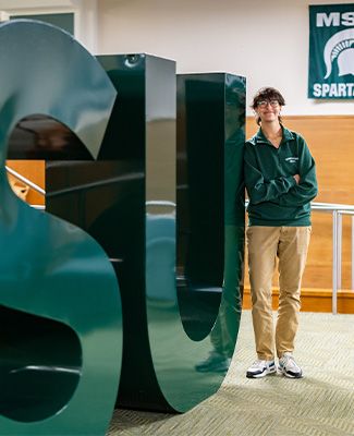 Joanna Gusis sits next to a statue of Sparty.