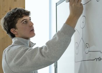 Engineering student Parker Strach solves equations on a whiteboard.