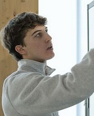 Engineering student Parker Strach studies at his laptop with a whiteboard in the background.