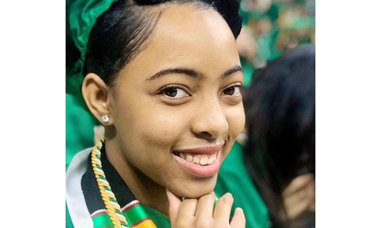 portrait of Sheritha Rayford, wearing her MSU green graduation cap and gown.